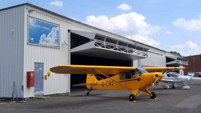 Kleinflugzeuge stehen vor einem Hangar