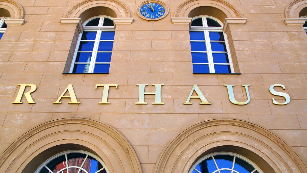 Fensterfront eines Rathauses mit Schriftzug über der Tür