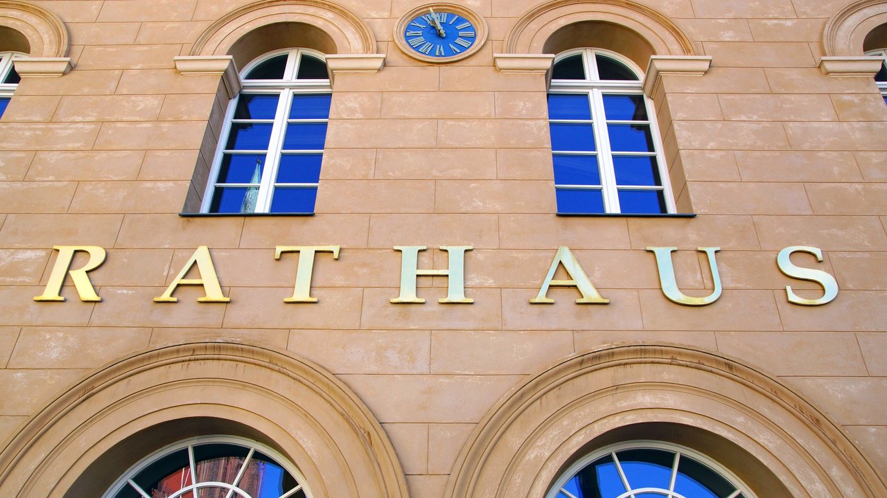 Fensterfront eines Rathauses mit Schriftzug über der Tür