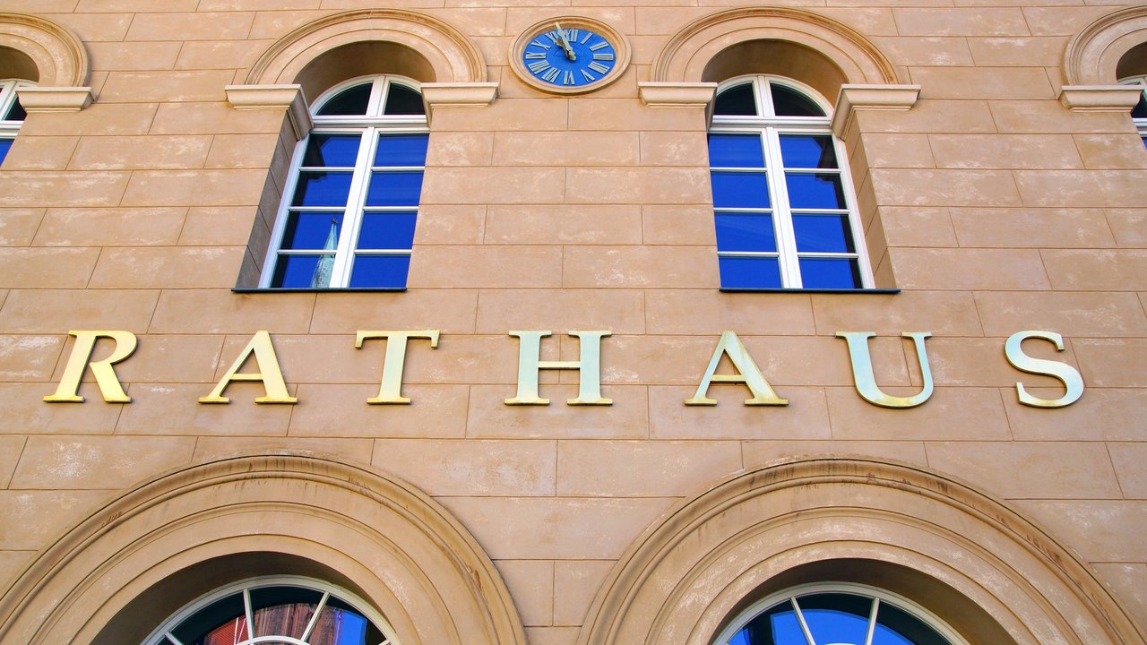 Fensterfront eines Rathauses mit Schriftzug über der Tür