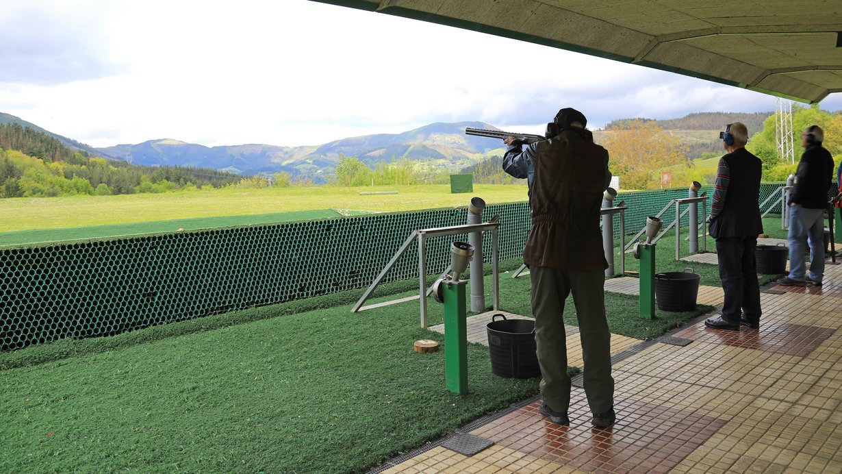 Drei Menschen stehen nebeneinander mit Gewehren im Anschlag an einem Schießstand