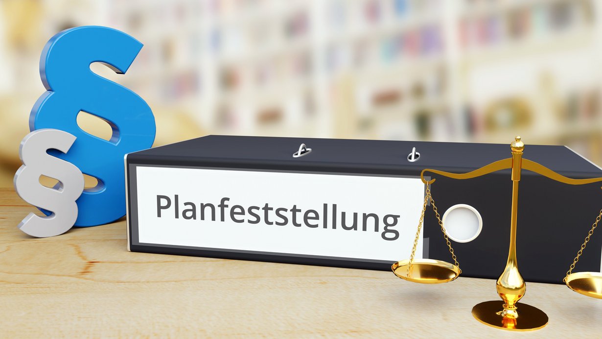 Ordner mit Schriftzug Planfeststellung, Waage und Paragraphenzeichen
