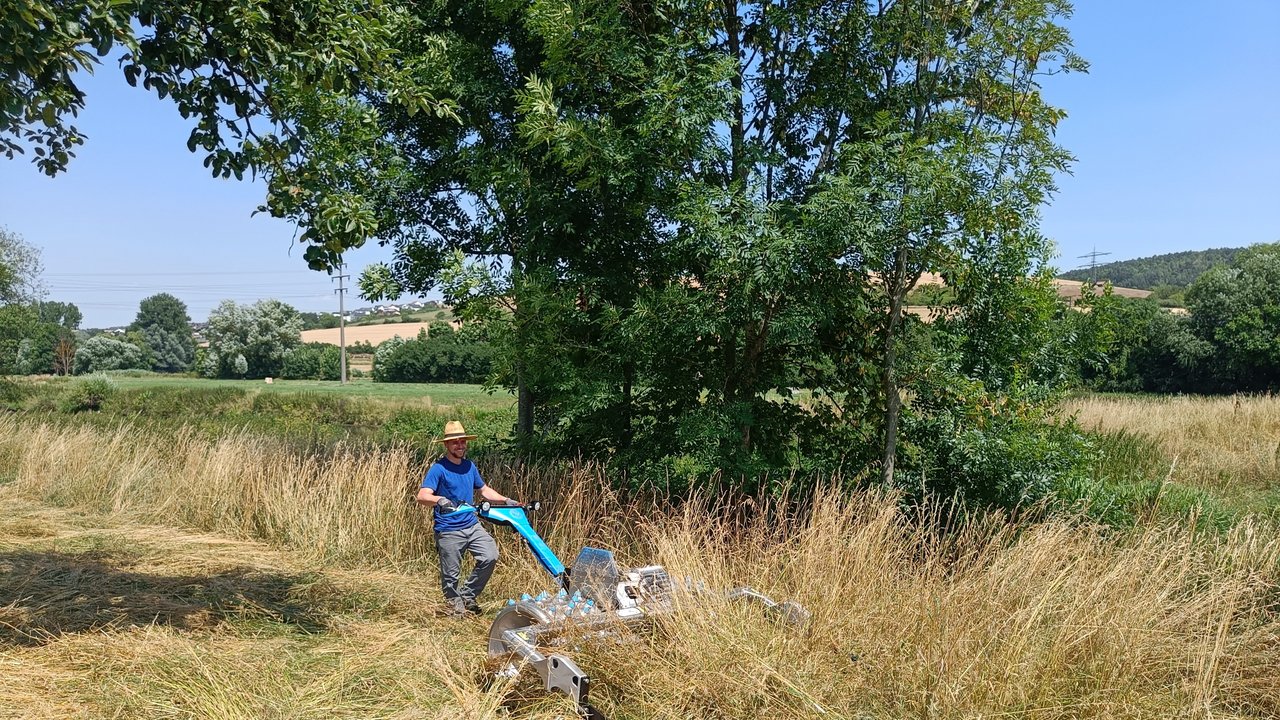 Ein Mann mäht eine Wiese