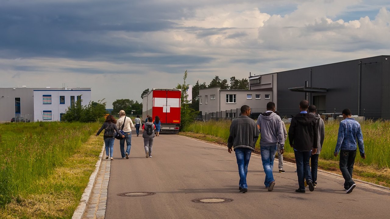 Bild zeigt Flüchtlinge auf einer Straße an der Seite Unterkünfte