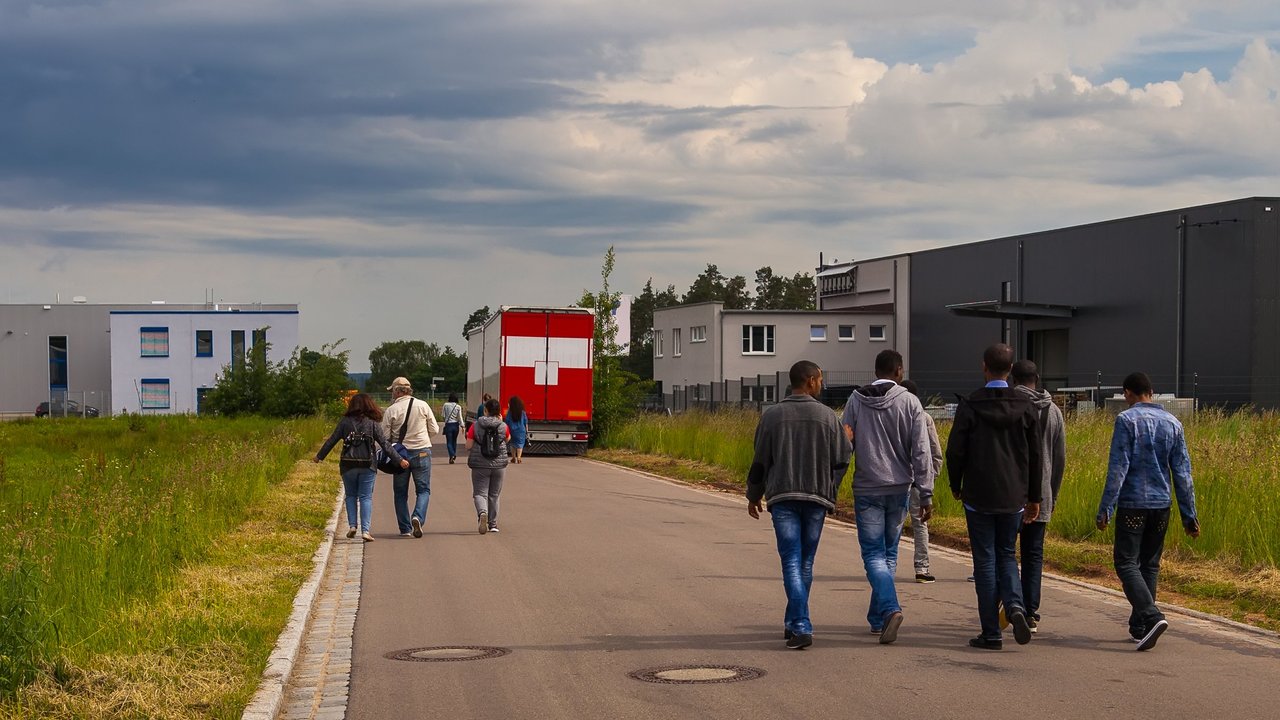 Bild zeigt Flüchtlinge auf einer Straße an der Seite Unterkünfte