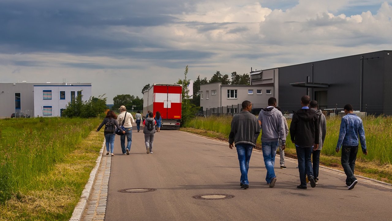 Bild zeigt Flüchtlinge auf einer Straße an der Seite Unterkünfte