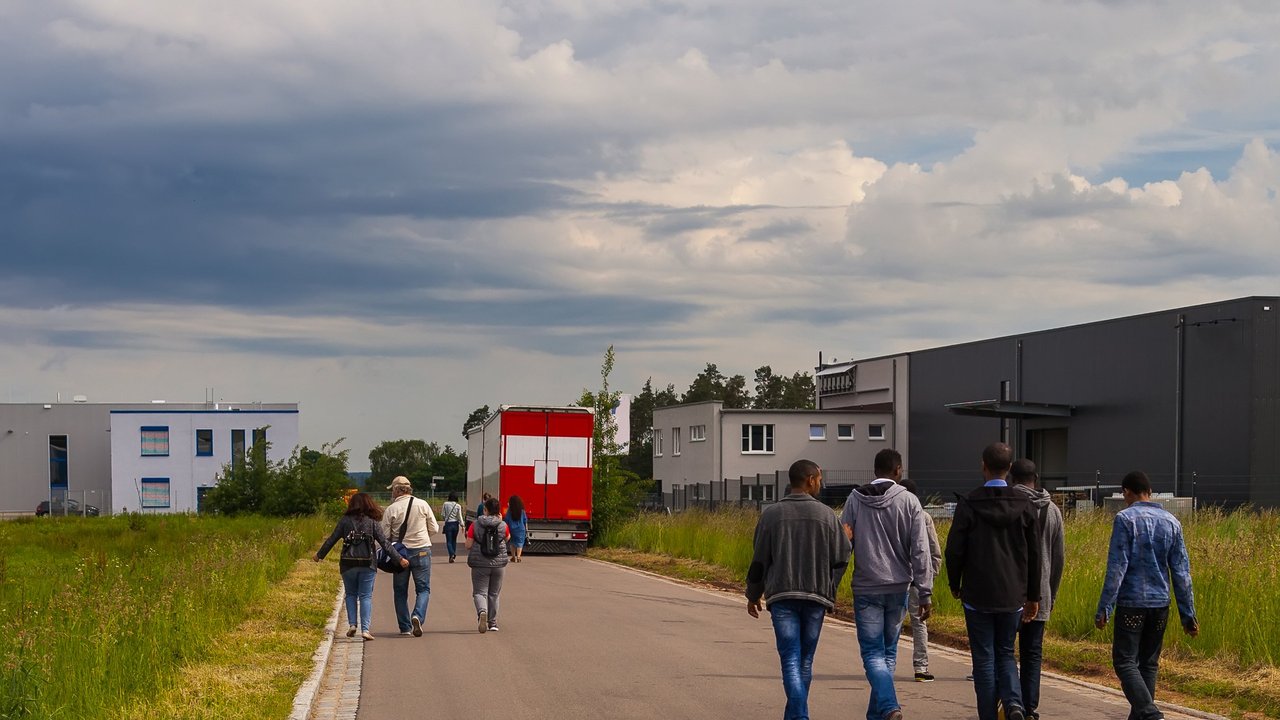 Symbolbild Bild zeigt Flüchtlinge auf einer Straße an der Seite Unterkünfte