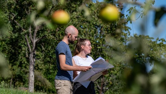 Bild zeigt Judith Kimmich mit einem Plan auf einer Wiese