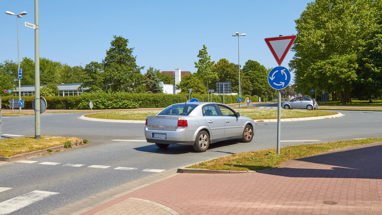 Ein graues Auto fährt in einen Kreisverkehr