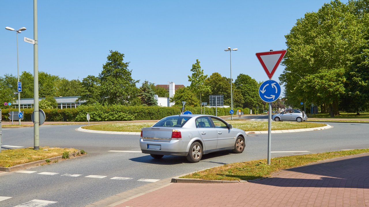 Ein graues Auto fährt in einen Kreisverkehr