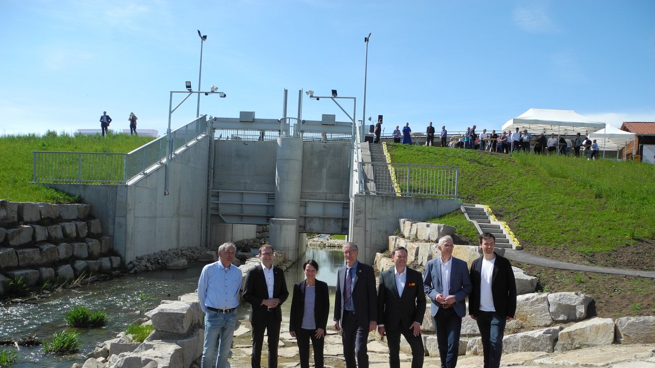 Landrat Roland Bernhard, Regierungspräsidentin Susanne Bay, Bürgermeister Lukas Rosengrün, Dr. Matthias Miller MdL, Bürgermeister a. D. Claus Unger, Jörg Koch und Tim Gfrörer vor der neuen Hochwasserschutzeinrichtung