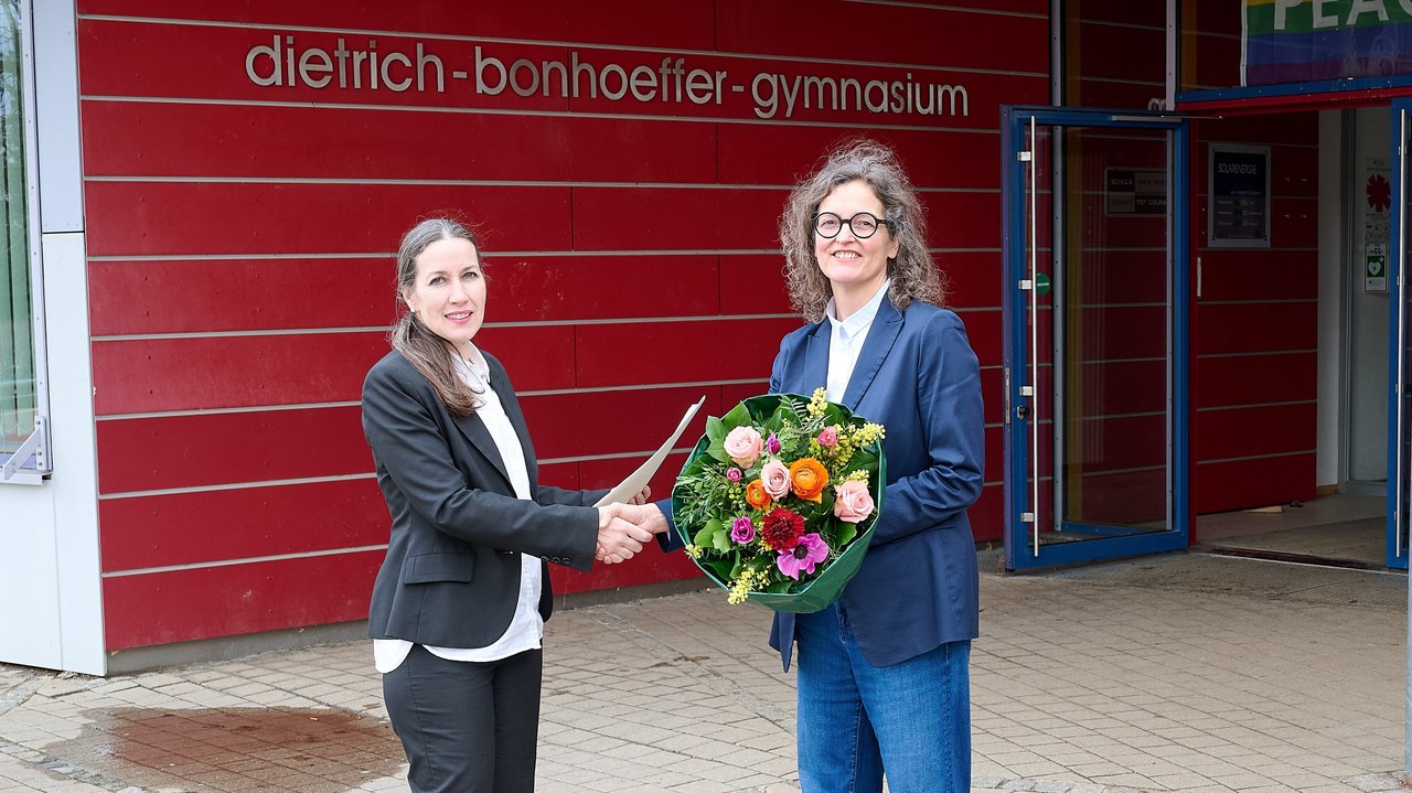 Nadja Schellhorn-Pintat (links), zuständige Referentin am Regierungspräsidium Stuttgart, über-reicht Nicole Reed (rechts) das Bestellungsschreiben von Kultusministerin Theresa Schopper. Dietrich-Bonhoeffer-Gymnasium Filderstadt