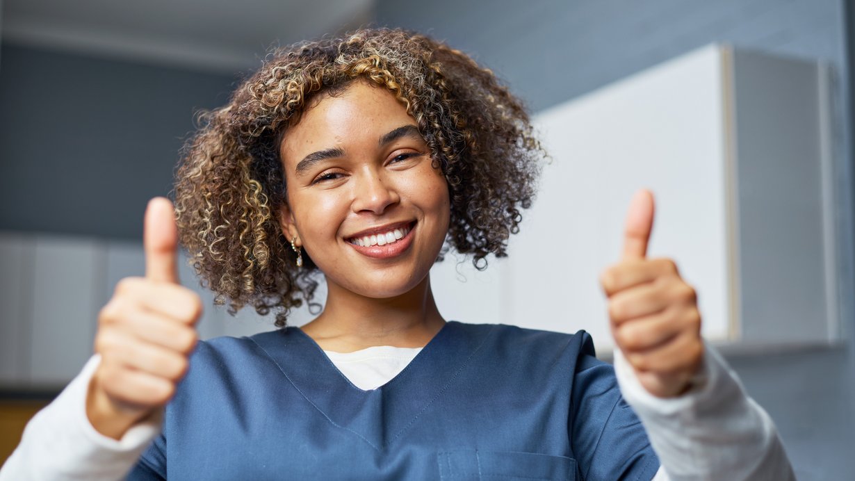 Bild zeigt eine Daumen drückende Krankenpflegerin