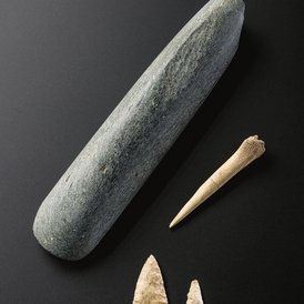 Bild zeigt Grabbeigaben aus der Jungsteinzeit: Steinbeil, Knochenpfriem und Pfeilspitzen aus Feuerstein.