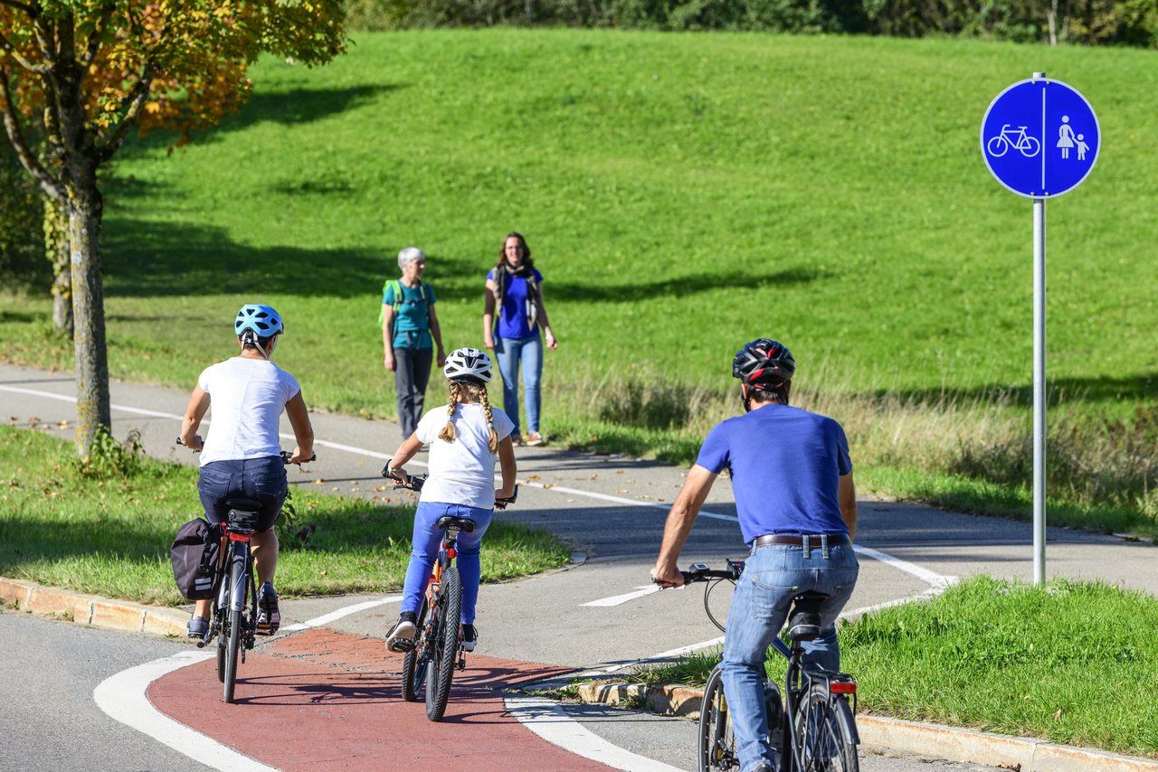Radfahrer befahren einen Übergang von der Straße auf einen kombinierten Rad- und Fußweg