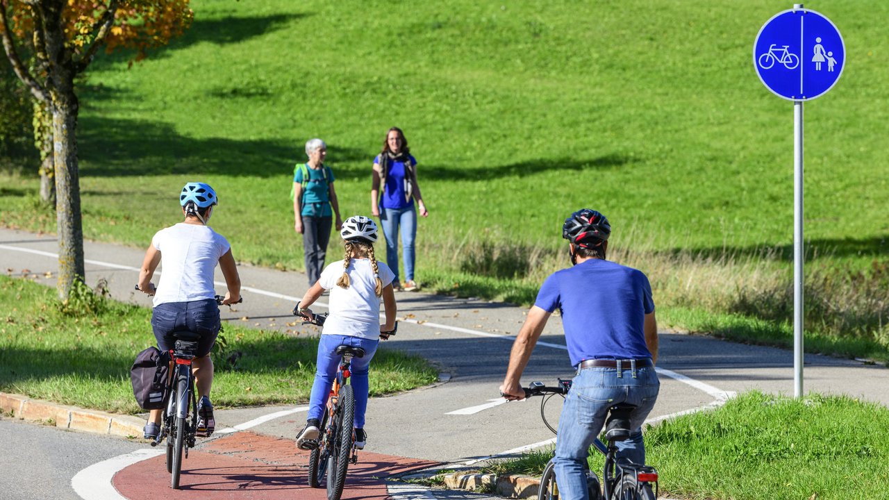 Radfahrer befahren einen Übergang von der Straße auf einen kombinierten Rad- und Fußweg
