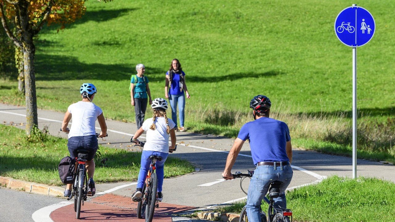 Fußgänger und Radfahrer auf einen Fuß- und Radweg Radfahrer befahren einen Übergang von der Straße auf einen kombinierten Rad- und Fußweg