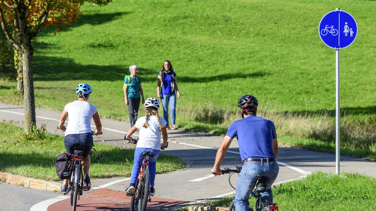 Radfahrer befahren einen Übergang von der Straße auf einen kombinierten Rad- und Fußweg