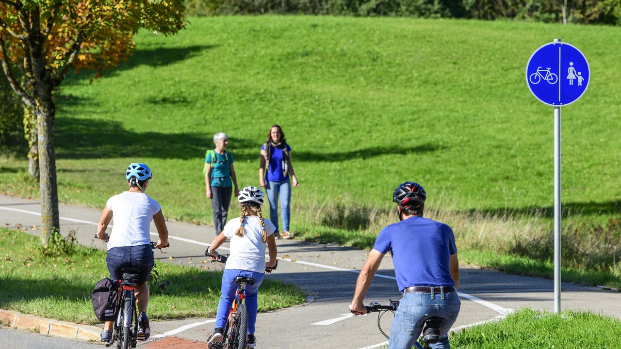 Radfahrer befahren einen Übergang von der Straße auf einen kombinierten Rad- und Fußweg