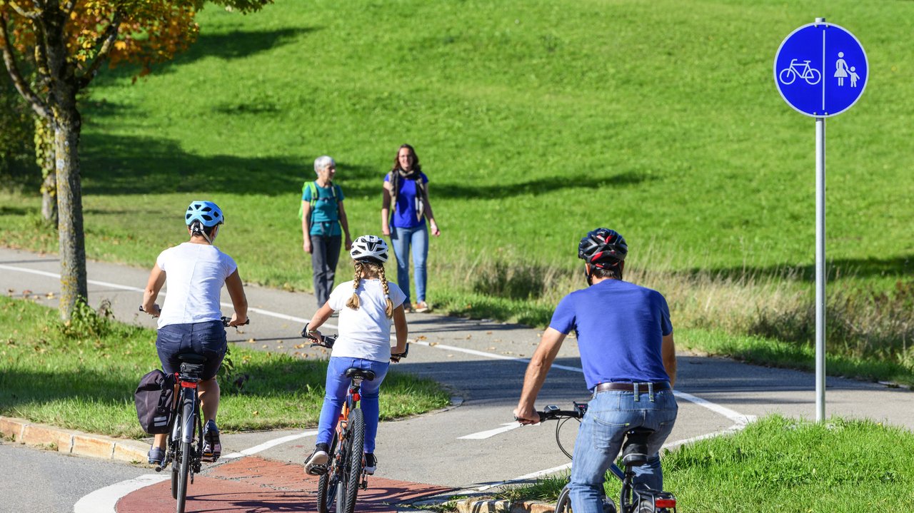 Radfahrer befahren einen Übergang von der Straße auf einen kombinierten Rad- und Fußweg
