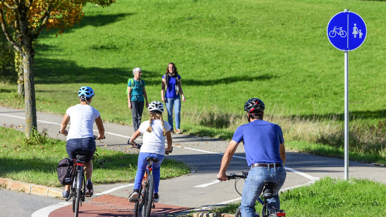 Radfahrer befahren einen Übergang von der Straße auf einen kombinierten Rad- und Fußweg