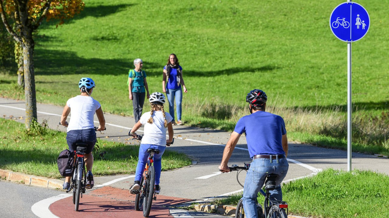 Radfahrer befahren einen Übergang von der Straße auf einen kombinierten Rad- und Fußweg