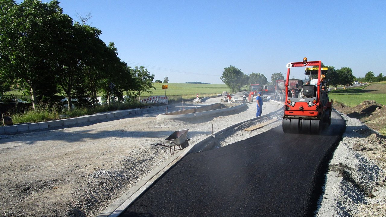 Foto: Die Arbeiten bei der Fahrbahndeckenerneuerung der L 1055 sind in vollem Gange: Der Radweg wird asphaltiert (rechts im Bild) und der Verkehrsteiler eingebaut (links im Bild).