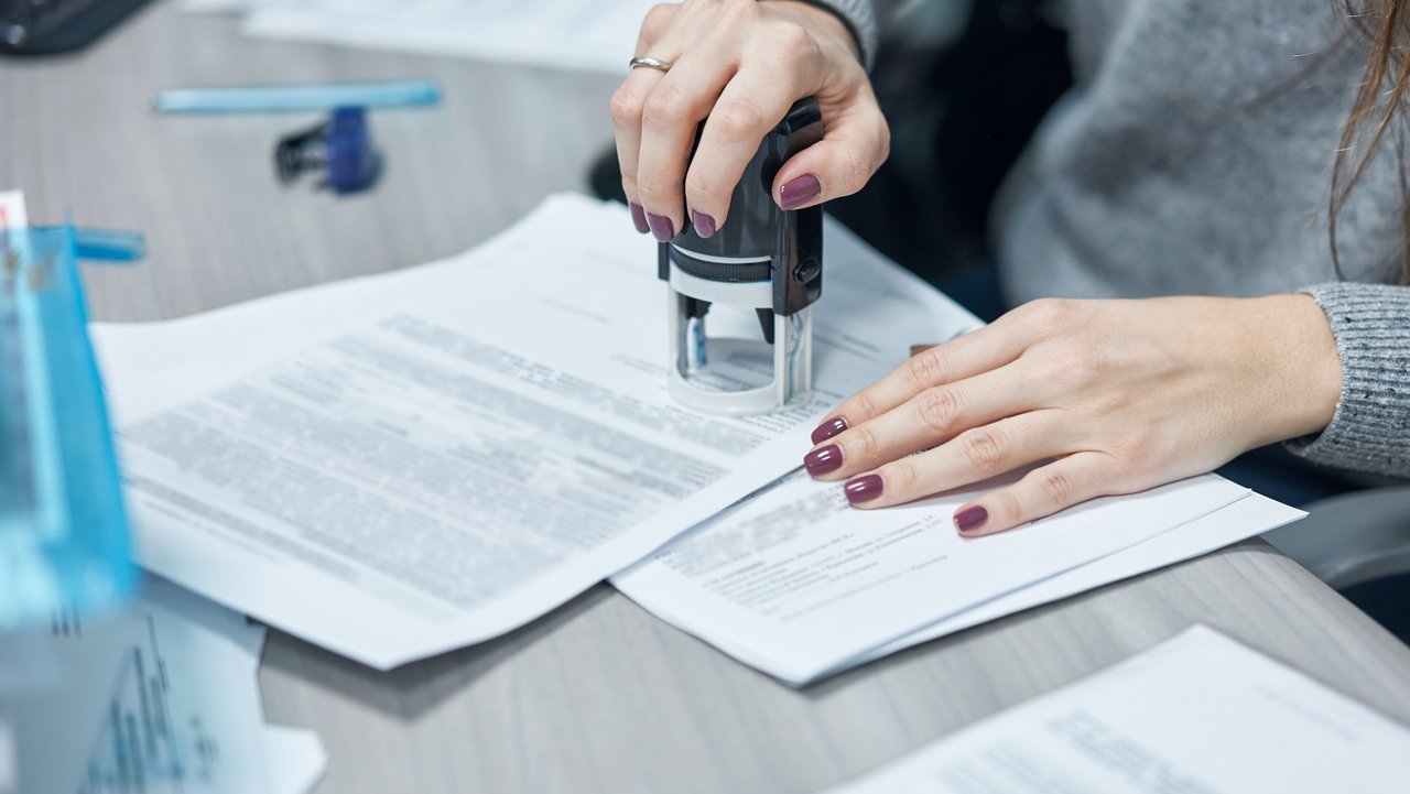 Frau am Schreibtisch, die eine Urkunde beglaubigt