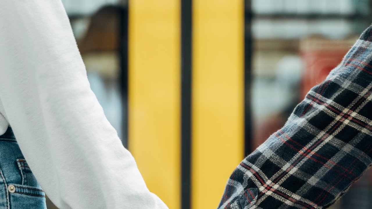 Zwei Jugendliche halten sich vor einem Zug an der Hand