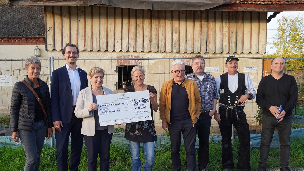 Ministerin Nicole Razavi übergibt den symbolischen Förderscheck vor dem Bahnwärterhaus