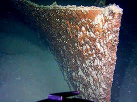 Nahaufnahme vom Bug des Rumpfes der SD Friedrichshafen II am Grund des Bodensees, von Steuerbord. Im Vordergrund der Greifarm des Unterwasserroboters 