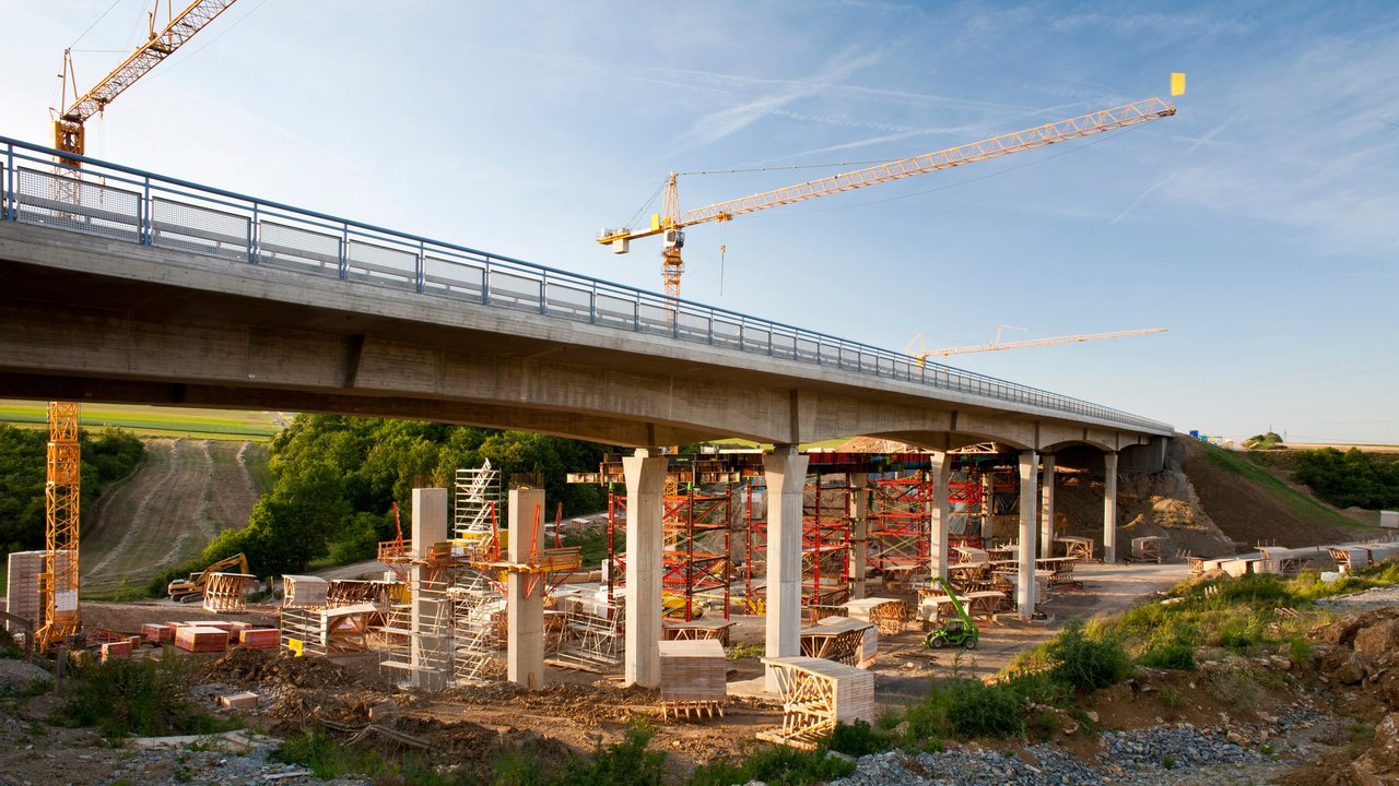 2 Kräne stehen hinter einer Brücke, die saniert werden soll