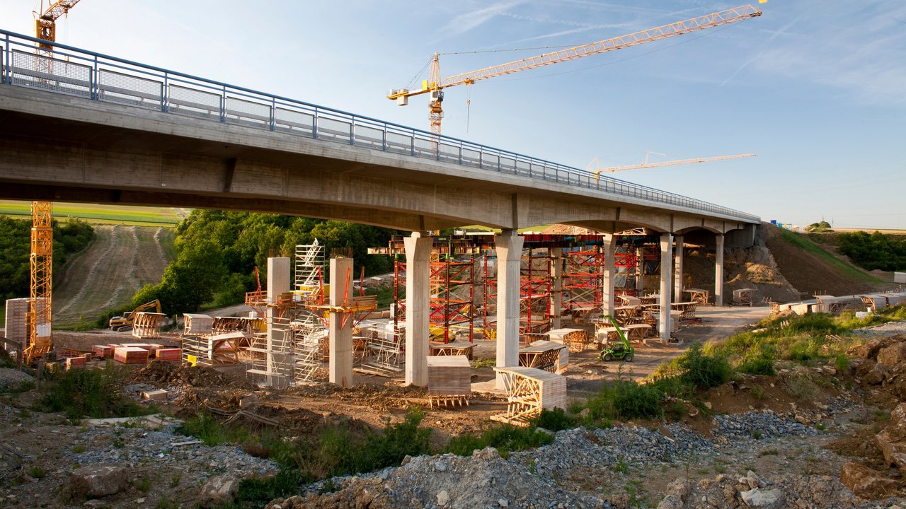 2 Kräne stehen hinter einer Brücke, die saniert werden soll