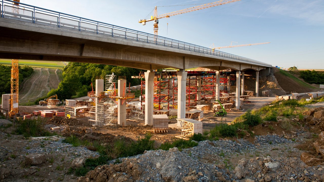 2 Kräne stehen hinter einer Brücke, die saniert werden soll