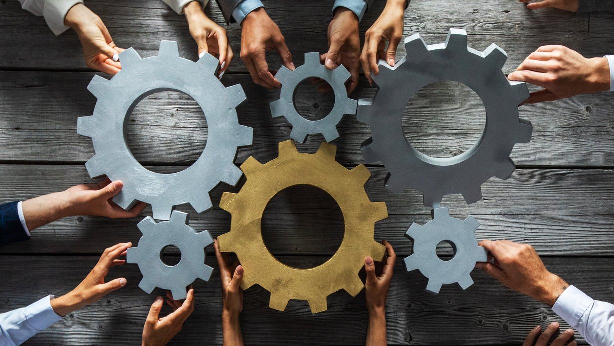 Bild zeigt Zahnräder mit Händen