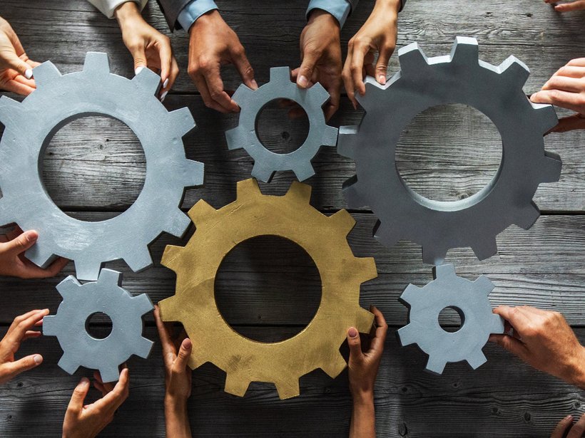 Bild zeigt Zahnräder mit Händen