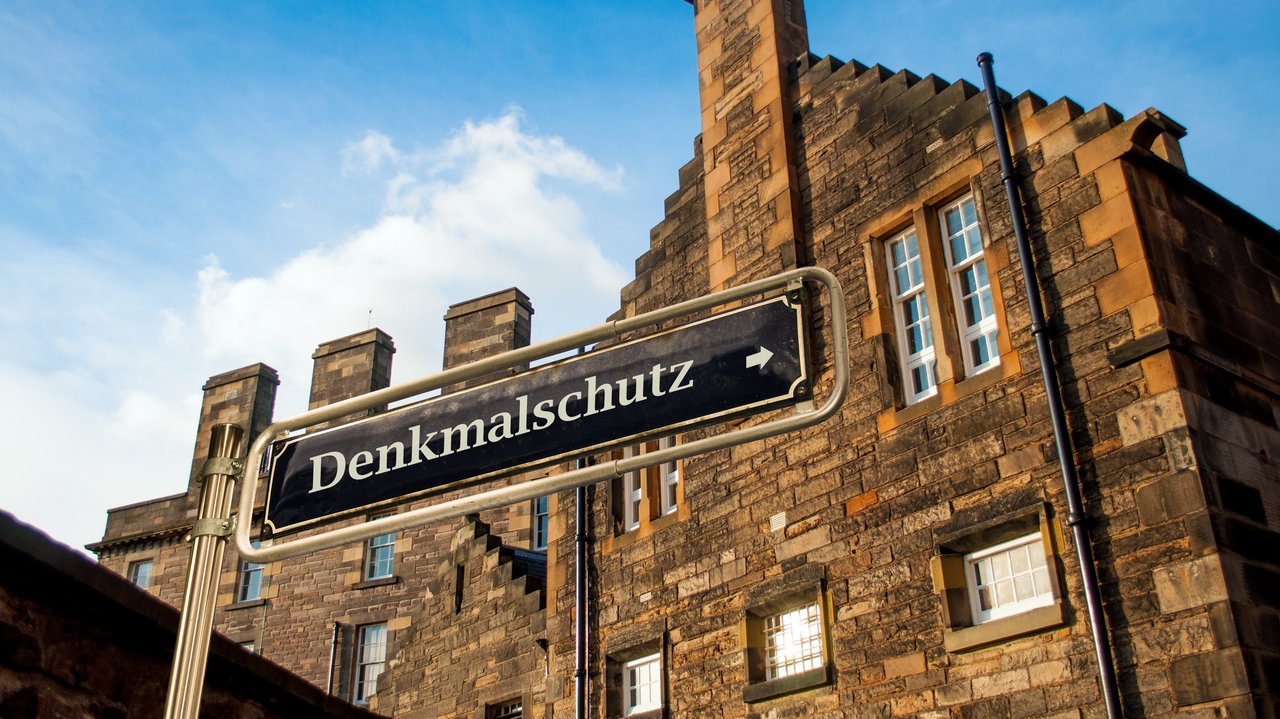 Backsteingebäude mit dem Schild "Denkmalschutz" im Vordergrund