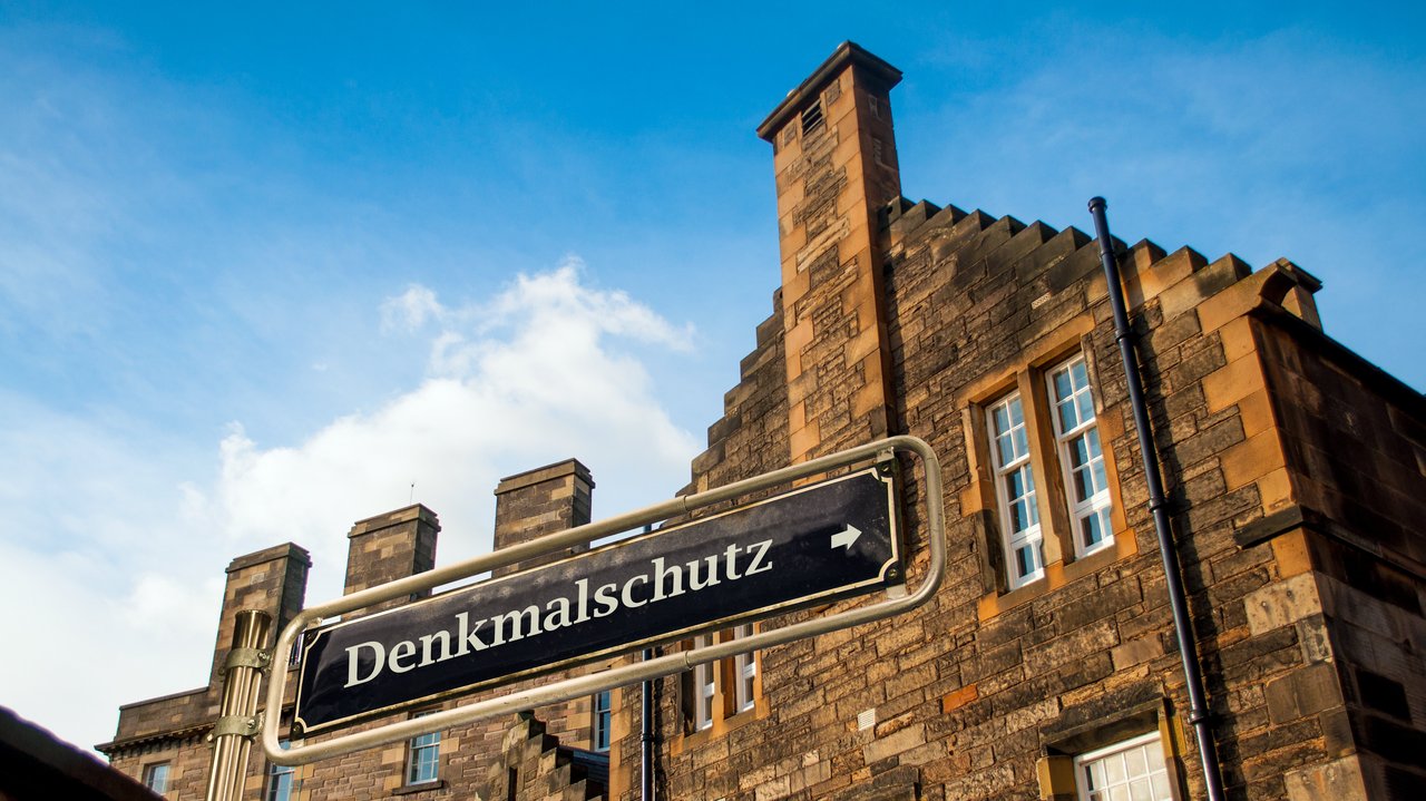 Backsteingebäude mit dem Schild "Denkmalschutz" im Vordergrund