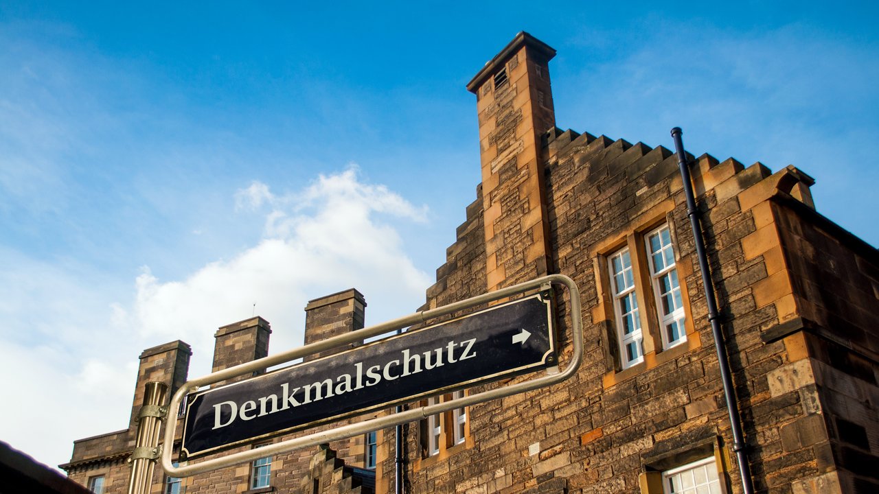 Backsteingebäude mit dem Schild "Denkmalschutz" im Vordergrund
