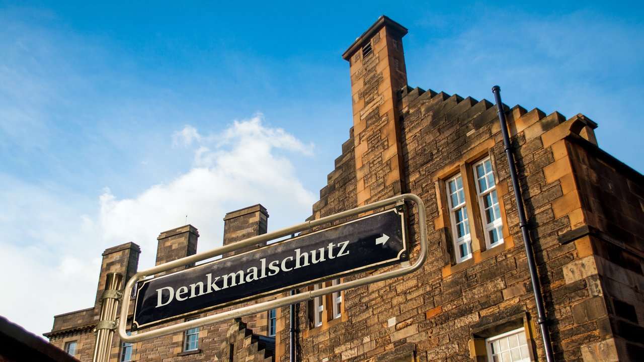 Backsteingebäude mit dem Schild "Denkmalschutz" im Vordergrund