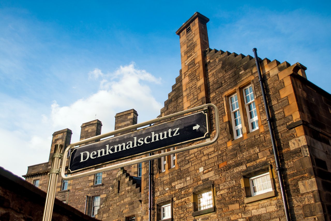 Backsteingebäude mit dem Schild "Denkmalschutz" im Vordergrund