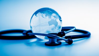Stethoskop umschlingt gläserne Weltkugel