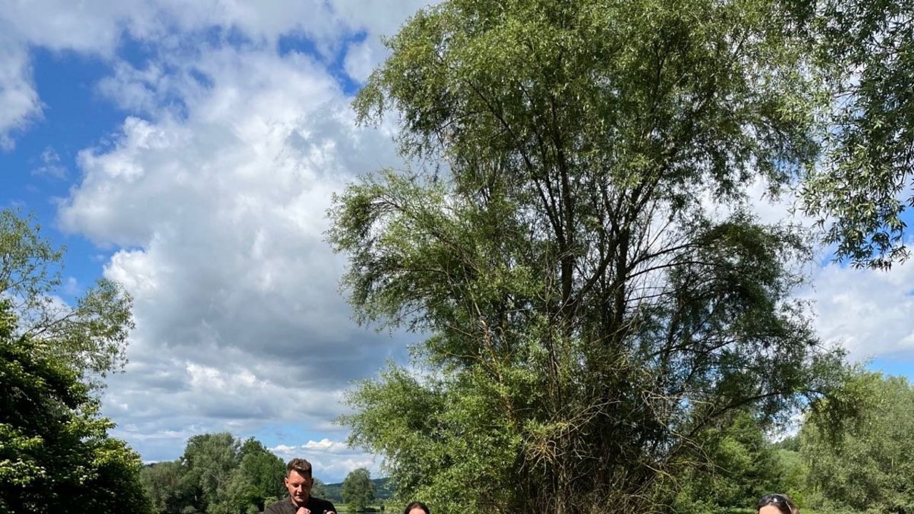 Bild zeigt den Referent für Naturschutz Lars Lochhaas vom RPS, zwei Frauen halten ein großes Plakat mit einem Biber, im Hintergrund ein See