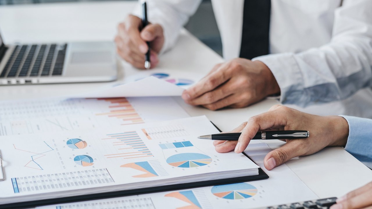 2 Männer sitzen an nebeneinander an einem Schreibtisch und erstellen eine Grafik