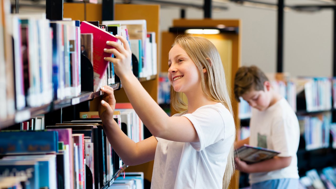Kinder suchen Bücher in einer Bibliothek