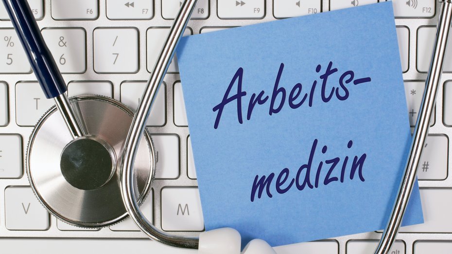 Stethoskop mit Tastatur Bild zeigt Stethoskop mit Tastatur und einem Notizzettel mit der Aufschrift "Arbeitsmedizin"