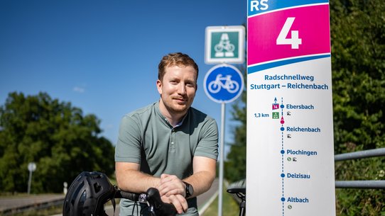 Bild zeigt Johann Achziger neben einem Radwegschild