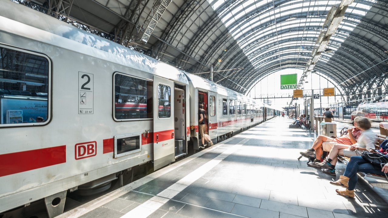 Bahnhof mit wartenden Menschen und wartendem Zug