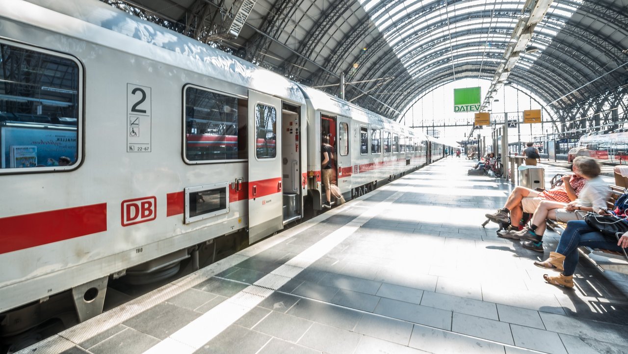 Bahnhof mit wartenden Menschen und wartendem Zug