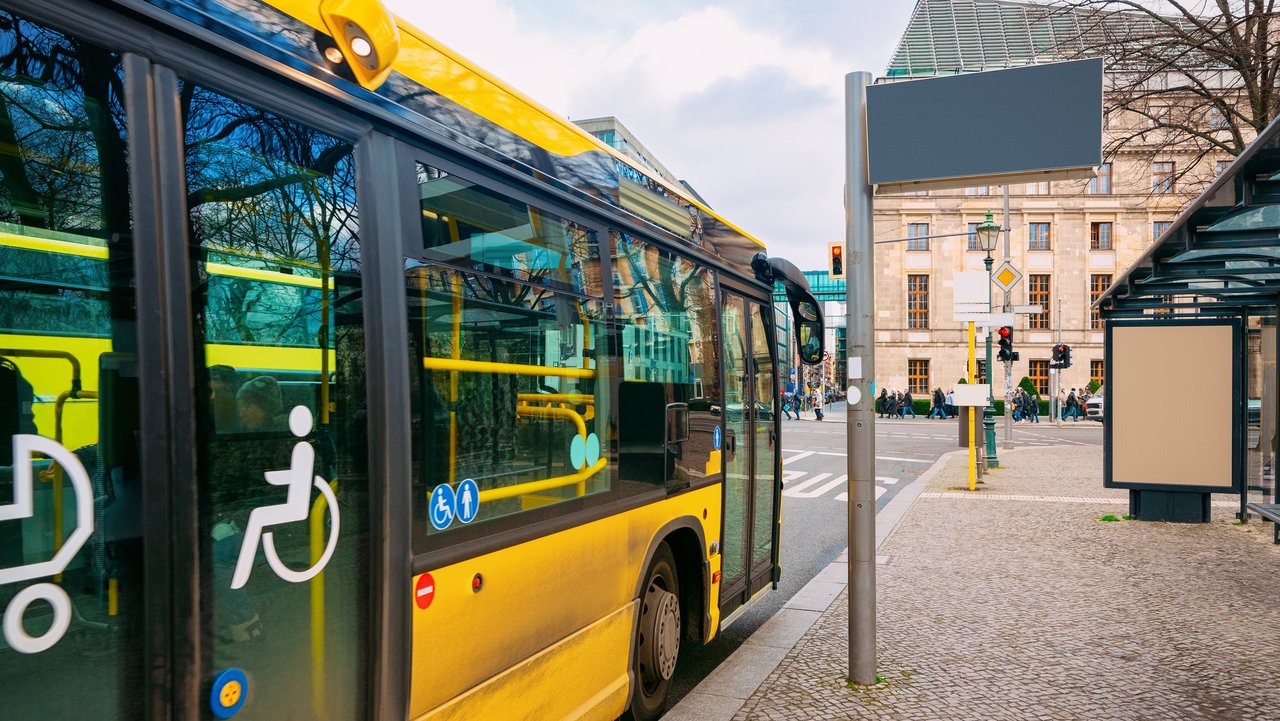 Gelber Bus mit barrierefreiem Einstieg hält an einer Bushaltestelle